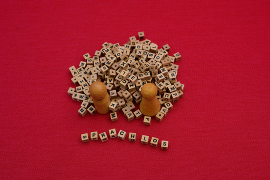 Sprachlos, zwei Holzfiguren mit Buchstabenwürfeln