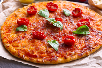 Pizza with basil and cherry tomatoes on parchment, closeup