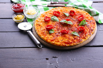 Pizza with basil and cherry tomatoes on wooden table, closeup