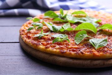 Pizza with basil on wooden table, closeup