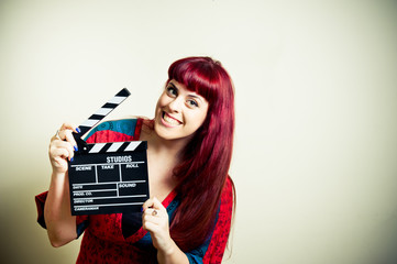 Young woman smiling showing movie clapper board