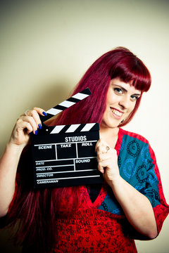 Young woman smiling showing movie clapper board