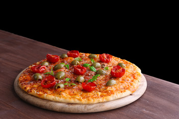 Tasty pizza with cherry tomatoes, green olives and herbs on wooden table on black background