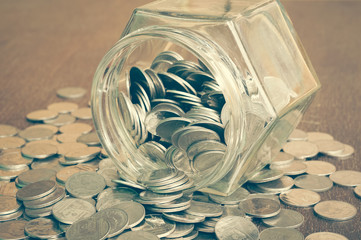 Coins spilling out of a glass bottle with filter effect retro vi