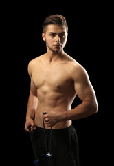 Fototapeta premium Muscle young man exercising with resistance band on dark background