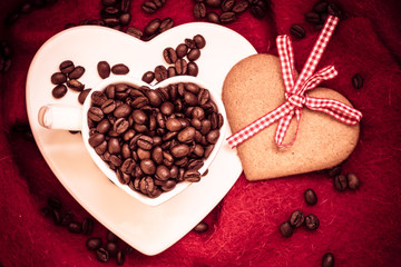 Coffee beans in heart shaped cup and dessert on red