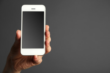 Hand holding mobile smart phone on gray background