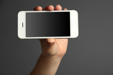 Hand holding mobile smart phone on gray background