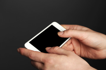 Hands holding mobile smart phone on gray background