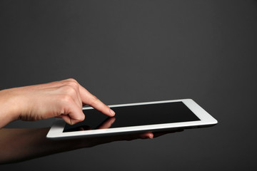 Hands holding tablet on gray background