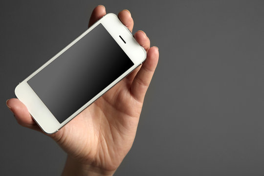 Hand holding mobile smart phone on gray background