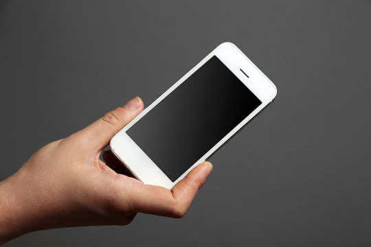 Hand holding mobile smart phone on gray background
