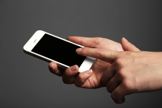 Hands holding mobile smart phone on gray background