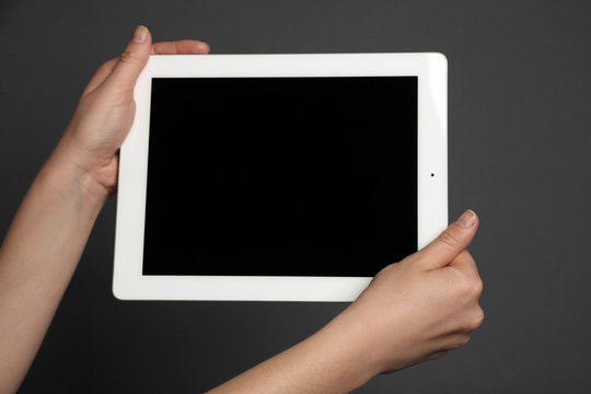 Hands holding tablet on gray background