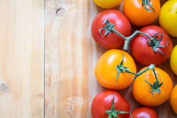 Color Tomatoes aligned on Right on top of wood table