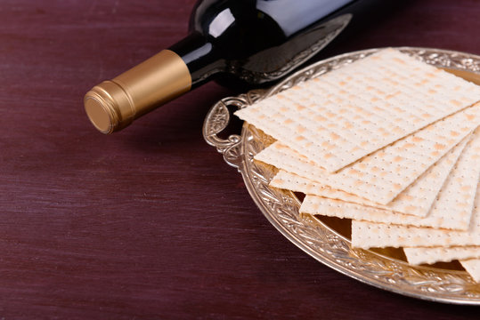 Matzo for Passover on metal tray with bottle of wine on table close up