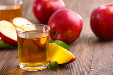 Glasses of apple juice and fruits on table close up