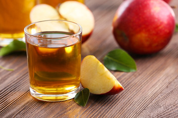 Glasses of apple juice and fruits on table close up