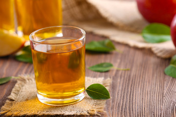 Glasses of apple juice and fruits on table close up