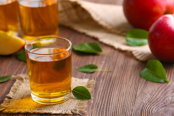 Glasses of apple juice and fruits on table close up