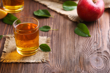 Glasses of apple juice and fruits on table close up