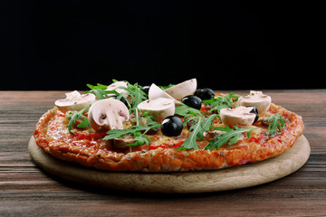 Tasty pizza with vegetables and arugula on black background