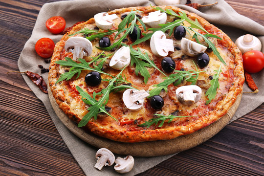 Tasty pizza with vegetables and arugula on table close up
