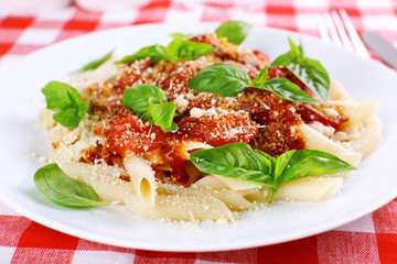 Pasta with tomato sauce and basil on table close up