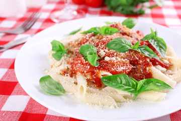 Pasta with tomato sauce and basil on table close up