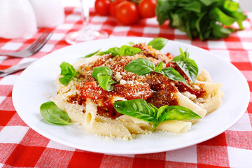 Pasta with tomato sauce and basil on table close up