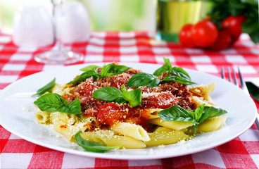 Pasta with tomato sauce and basil on table close up