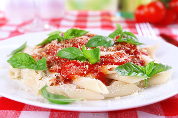 Pasta with tomato sauce and basil on table close up