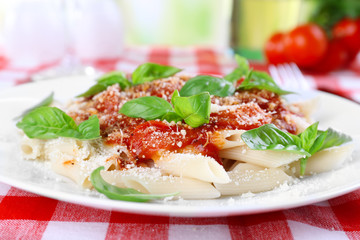 Pasta with tomato sauce and basil on table close up