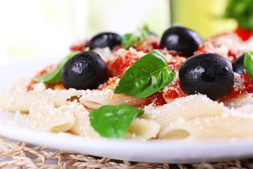 Pasta with tomato sauce and basil on table close up