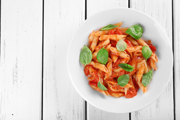 Pasta with tomato sauce and basil on wooden table close up