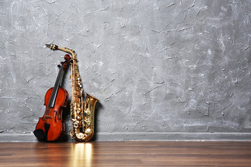 Violin and saxophone on gray wall background
