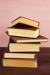 Stack of books on wooden table on pink wall background