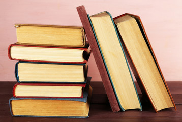 Stack of books on wooden table on pink wall background