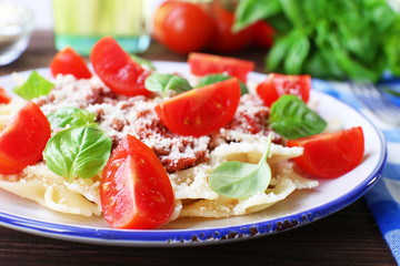 Pasta bolognese with cherry tomatoes in white plate on wooden table, closeup