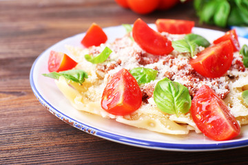 Pasta bolognese with cherry tomatoes in white plate on wooden table, closeup