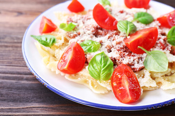 Pasta bolognese with cherry tomatoes in white plate on wooden table, closeup
