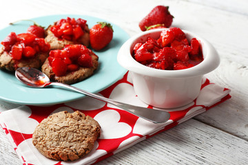 Cookies with fresh strawberry in plate on wooden table, closeup