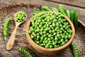Fresh green peas in bowl on wooden tray, closeup