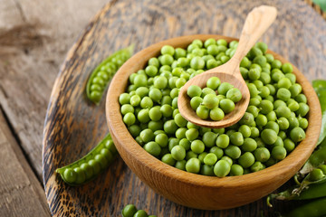 Fresh green peas in bowl on wooden tray, closeup