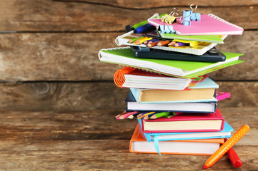 Stack of books and stationery on wooden background