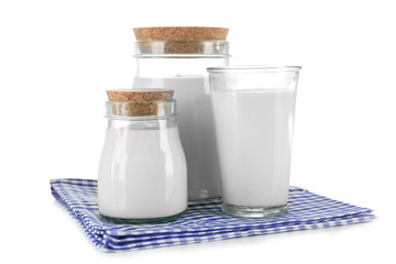 Jars and glass of milk on wooden table, on white background