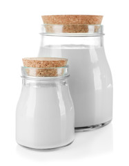 Glass jars of milk on wooden table, on white background