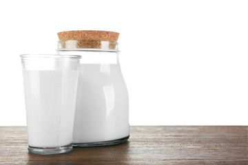 Jar and glass of milk on wooden table, on white background