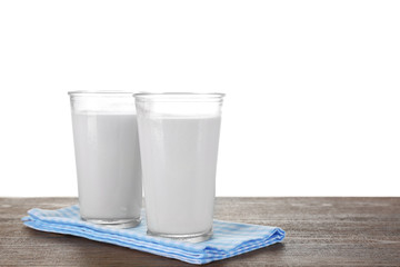 Glasses of milk on wooden table, on white background