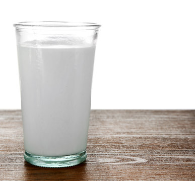 Glass of milk on wooden table, on white background